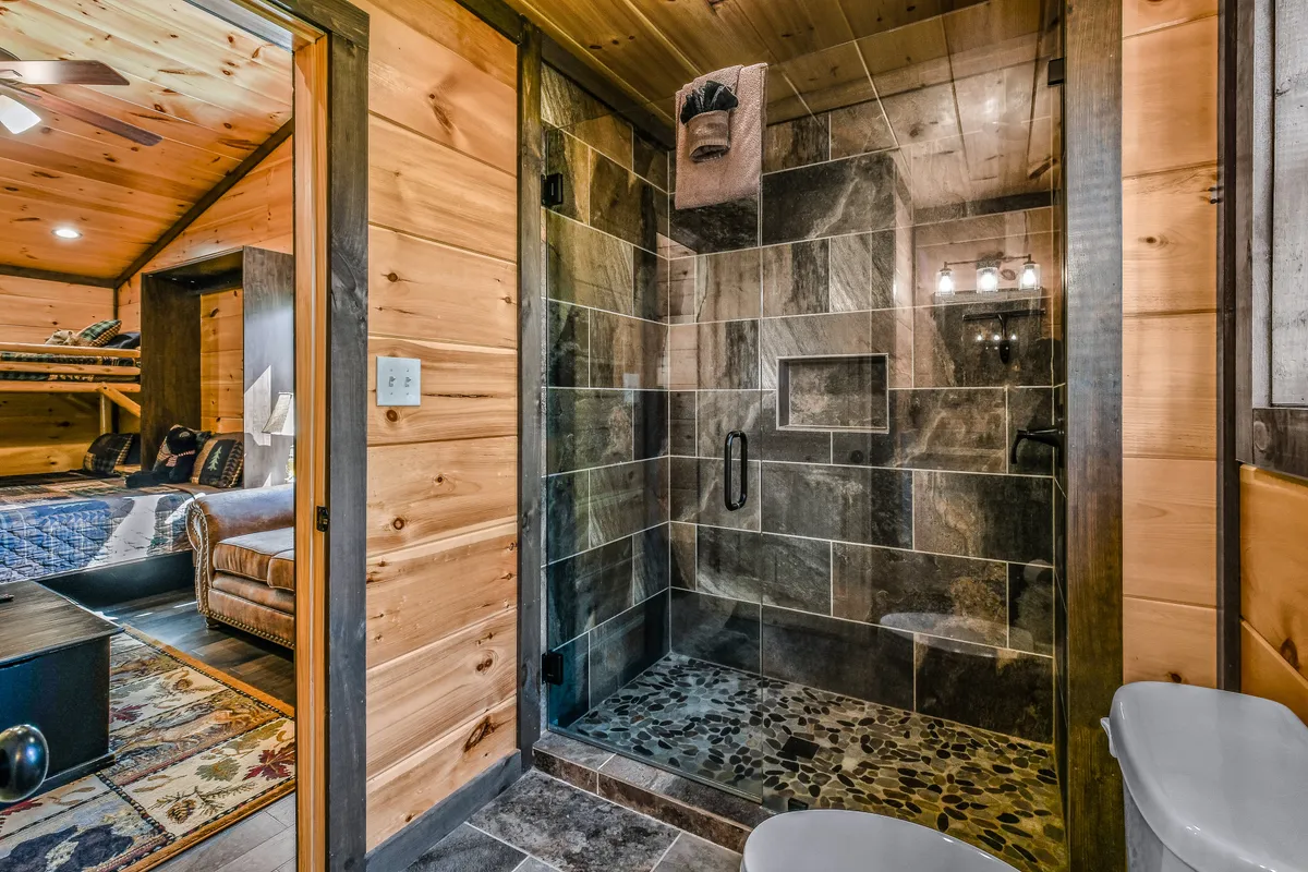A modern, inviting bathroom featuring a spacious walk-in shower with natural wood paneling and luxurious fixtures. The atmosphere is tranquil and spa-like, perfect for refreshing or relaxing at any time of day.