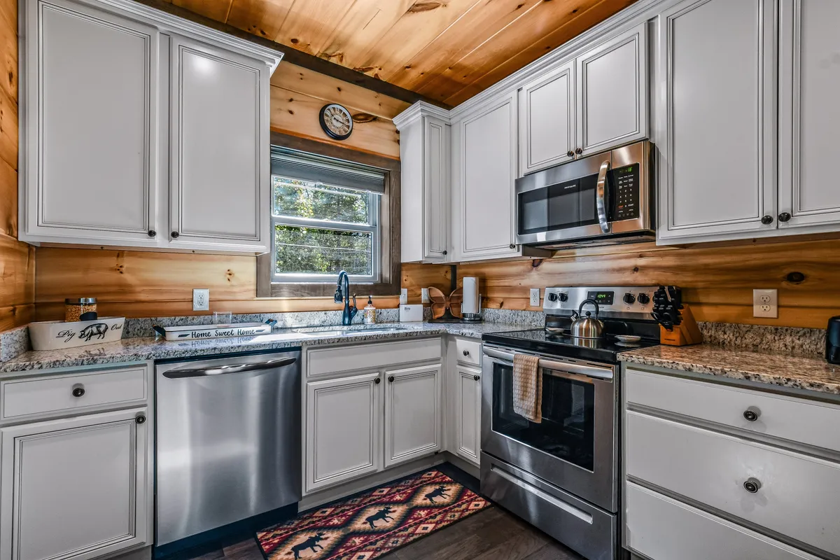 A well-appointed kitchen with granite countertops, stainless steel appliances, a wooden ceiling, and a warm decorative rug. The kitchen is bright and inviting, offering ample space for meal preparation and socializing.