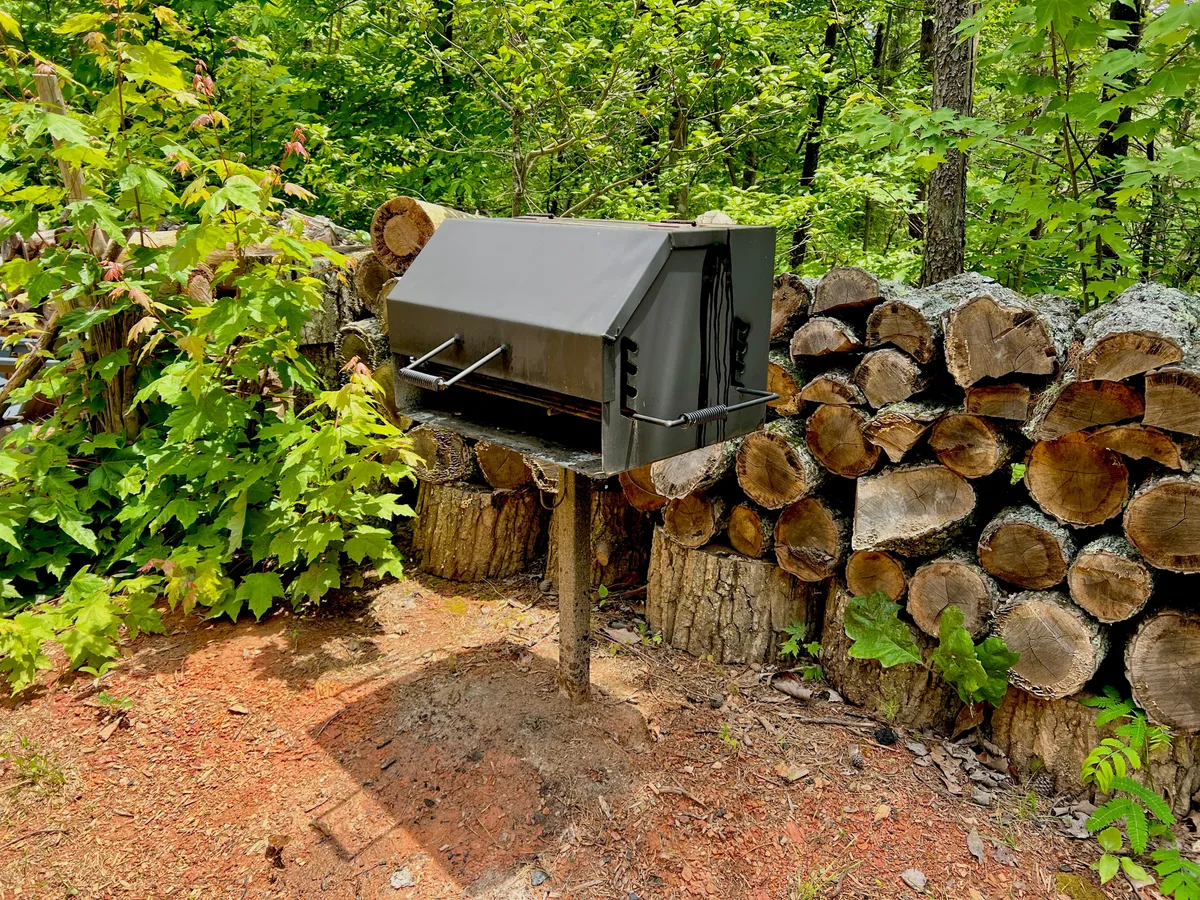 The image features a rustic black mailbox, stacked logs, and lush greenery, evoking a sense of community and connection to the surrounding environment. It hints at the communal perks and neighborly touches found within the resort area.