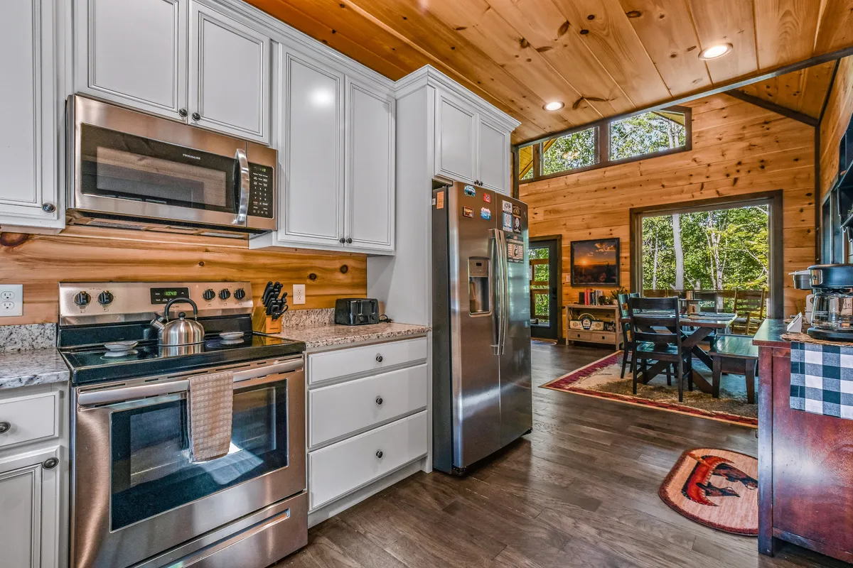 This image showcases a spacious, fully equipped kitchen with stainless steel appliances, granite countertops, and large windows letting in natural light. The communal setting is perfect for guests looking to save on dining by preparing meals together.